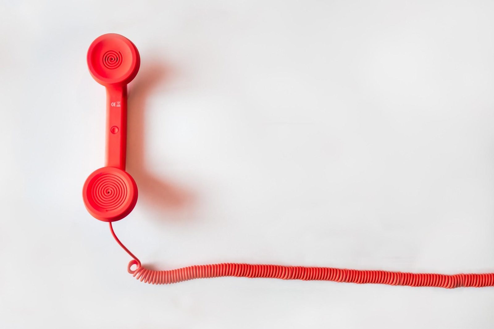 A picture of a red phone used for cold calling with a cord.