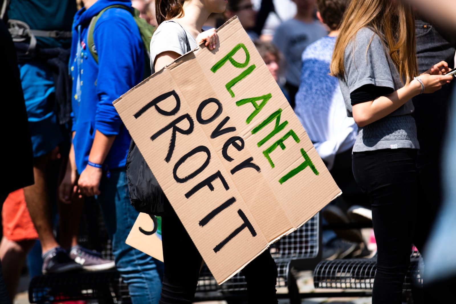 Eco friendly marketing. A group of environmental protesters, one carrying a cardboard sign reading, “Planet over Profit”.